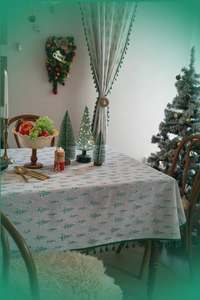 Detailed view of Christmas tablecloth with green pine tree prints and tassel fringe edge
