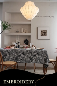 Detailed view of embroidery featuring leopards and tropical plants on a black tablecloth