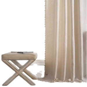 Classic beige jacquard curtain with damask patterns and tassel trim in soft lighting