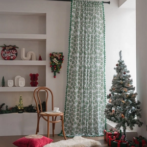 White Christmas curtain with green holly leaf patterns and festive tassel trim