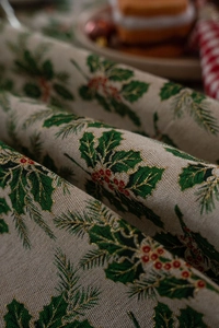 Macro view of Christmas holly leaf print fabric with gold foil details and linen texture