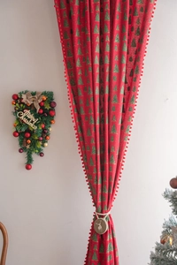Close-up of red Christmas curtains with gold tree patterns and reindeer tiebacks