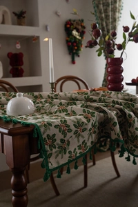 Close-up of Christmas table runner with holly berry print and green tassel trim detail