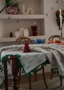 Close-up of Christmas tablecloth featuring green pine tree prints and tassel edge details