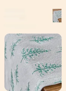 Detail of green branch print with gold foil process on white textured table runner