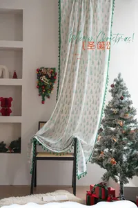 Detail of white Christmas curtain featuring green pine tree prints and tassel fringe
