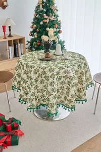 Detail of Christmas round tablecloth with holly berry print and dark green fringe trim
