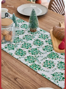 Close-up of white festive table runner with green and gold Christmas flower pattern