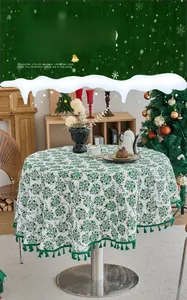 Detail of Christmas round tablecloth with green pine print and matching tassel fringe edges