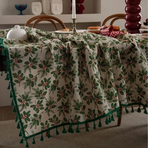 Christmas tablecloth with holly leaves, red berries, and green tassels on cream fabric