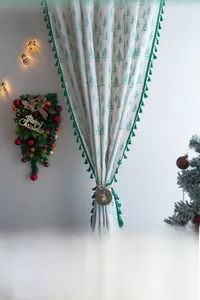 Detailed view of green fir tree patterns and fringe trim on Christmas curtain
