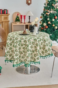 Detail of round Christmas tablecloth with holly berry patterns and green tassels