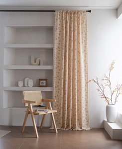 Detailed close-up of cream floral curtains with white tassel fringe and linen texture