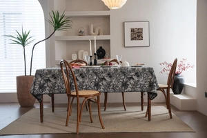 Macro view of floral jacquard tablecloth with black botanical embroidery on white fabric