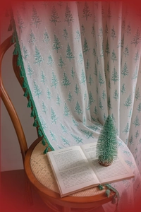Detail of cream fabric curtain with green pine tree prints and tassel fringe trim