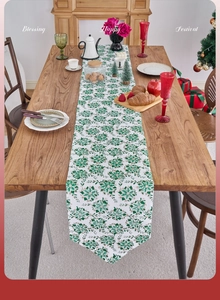 Detail of Christmas table runner with green and gold festive patterns on white fabric