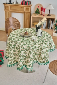 Detail of Christmas round tablecloth with green leaves pattern and hanging green tassels