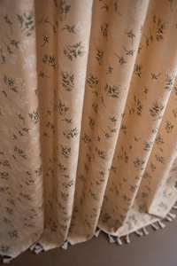 Detailed macro view of floral print curtain fabric with white tassels and linen texture