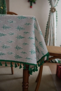 Detail of Christmas tablecloth with green pine tree prints and fine green fringe tassels