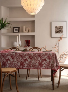 Detail of red and white floral jacquard tablecloth with elegant red pompom fringe tassels