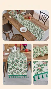 Detail of Christmas table runner with green holly leaves, red berries and tassel fringe