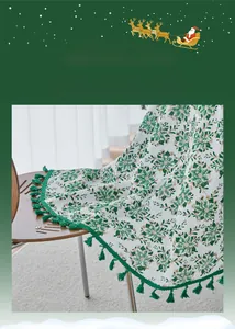Close-up of Christmas tablecloth with green pine needles, gold accents and fringe trim