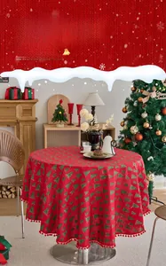 Detail of red Christmas tablecloth with green tree prints and decorative pom-poms