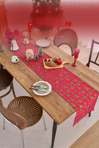 Detail of red Christmas table runner with green tree patterns and handcrafted tassels