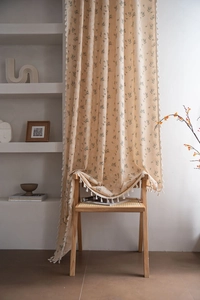 Close-up of floral print curtain fabric with elegant white tassel fringe detailing