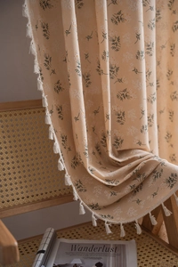 Detail of floral print curtain with delicate white cotton tassels and textured fabric