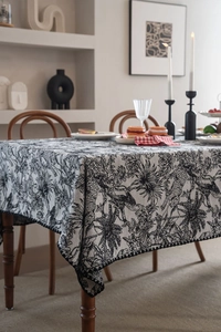 Detailed texture of jacquard tablecloth with black tropical plants and pom-pom trim