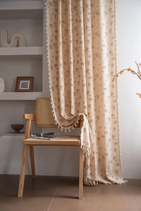 Close-up of floral print curtain with cotton tassel trim on cream cotton linen fabric