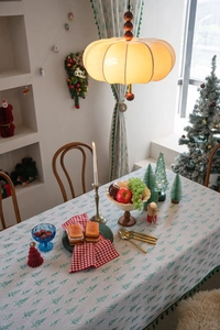 Close-up of green Christmas tree patterns on beige tablecloth with elegant green tassels