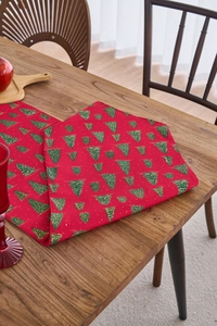 Detail of red Christmas table runner featuring gold-stamped green trees on wood surface