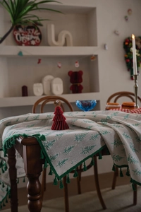 Close-up of festive Christmas tablecloth with green tree prints and elegant fringe edges
