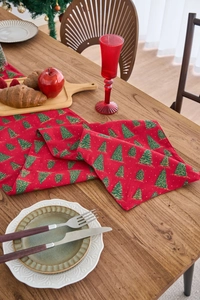 Detail of red Christmas table runner with gold tree prints on a festive wooden table