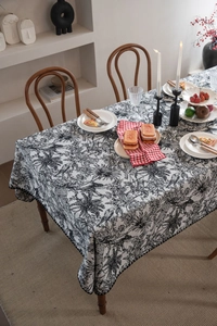 Close-up of black tropical botanical print jacquard tablecloth with scalloped wavy edges