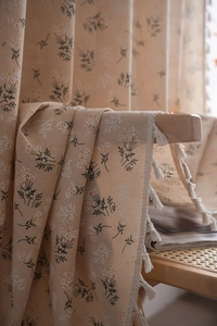 Close-up of cream floral curtain fabric with delicate white cotton tassel fringe detail