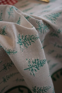 Detail of Christmas tablecloth fabric with sparkling green glitter pine tree patterns