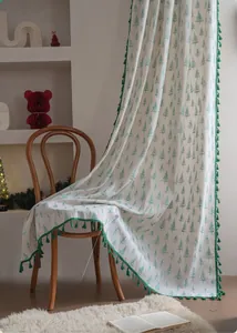 Detail of Christmas curtain with green pine trees and elegant tassel trim on white fabric