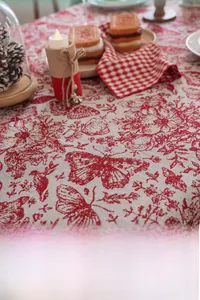 Detailed close-up of red and white festive jacquard tablecloth with floral butterfly patterns