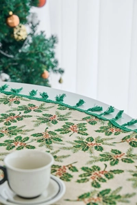 Detail of Christmas table runner with pine leaves, red berries and green tassels