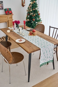 Detail of Christmas table runner with green tree patterns and dark green tassels