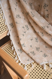Detail of floral beige fabric with natural cotton tassels and delicate small flower prints