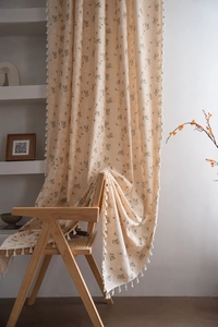 Detail of cream floral curtain fabric featuring delicate tassels and vintage pattern