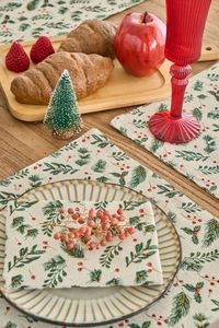 Detail of Christmas table mat with green pine branches and red berry prints on fabric