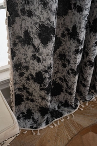Detail of curtain featuring black and white ink splash pattern with cream tassel fringe