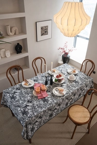 Detailed close-up of a rectangular tablecloth featuring black and white forest sketch patterns