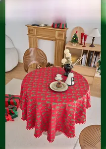 Detailed macro view of festive red Christmas tablecloth with pine tree prints and pom-pom trim