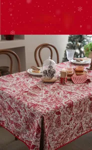 Detail of red and white Christmas tablecloth featuring floral patterns and pom-pom trim